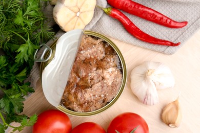 Photo of Canned meat in tin can and other products on wooden table, top view