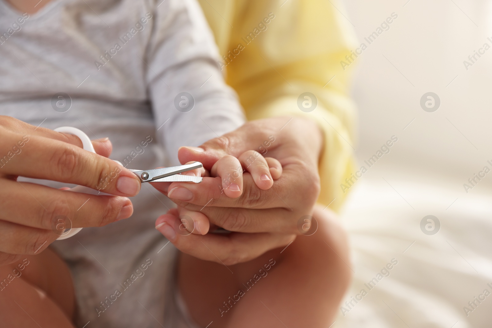 Photo of Mother cutting her cute little baby's nails at home, closeup