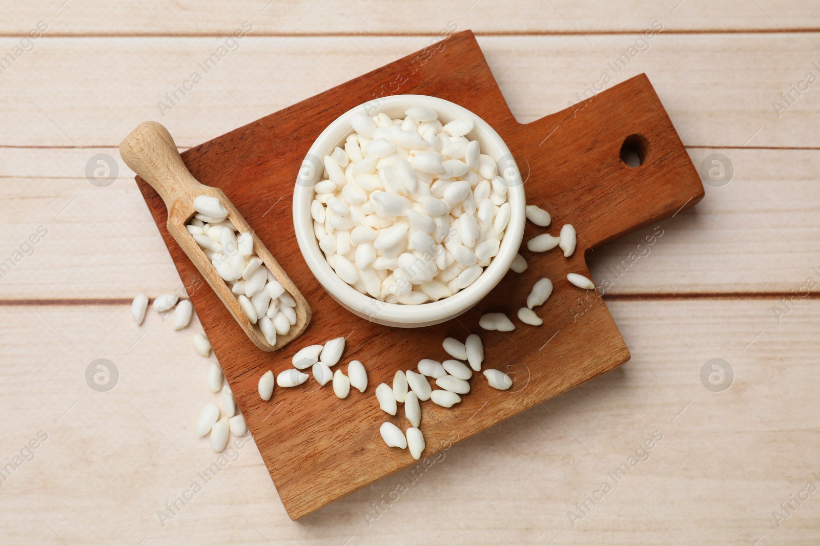 Photo of Bowl and scoop with puffed rice on white wooden table, top view