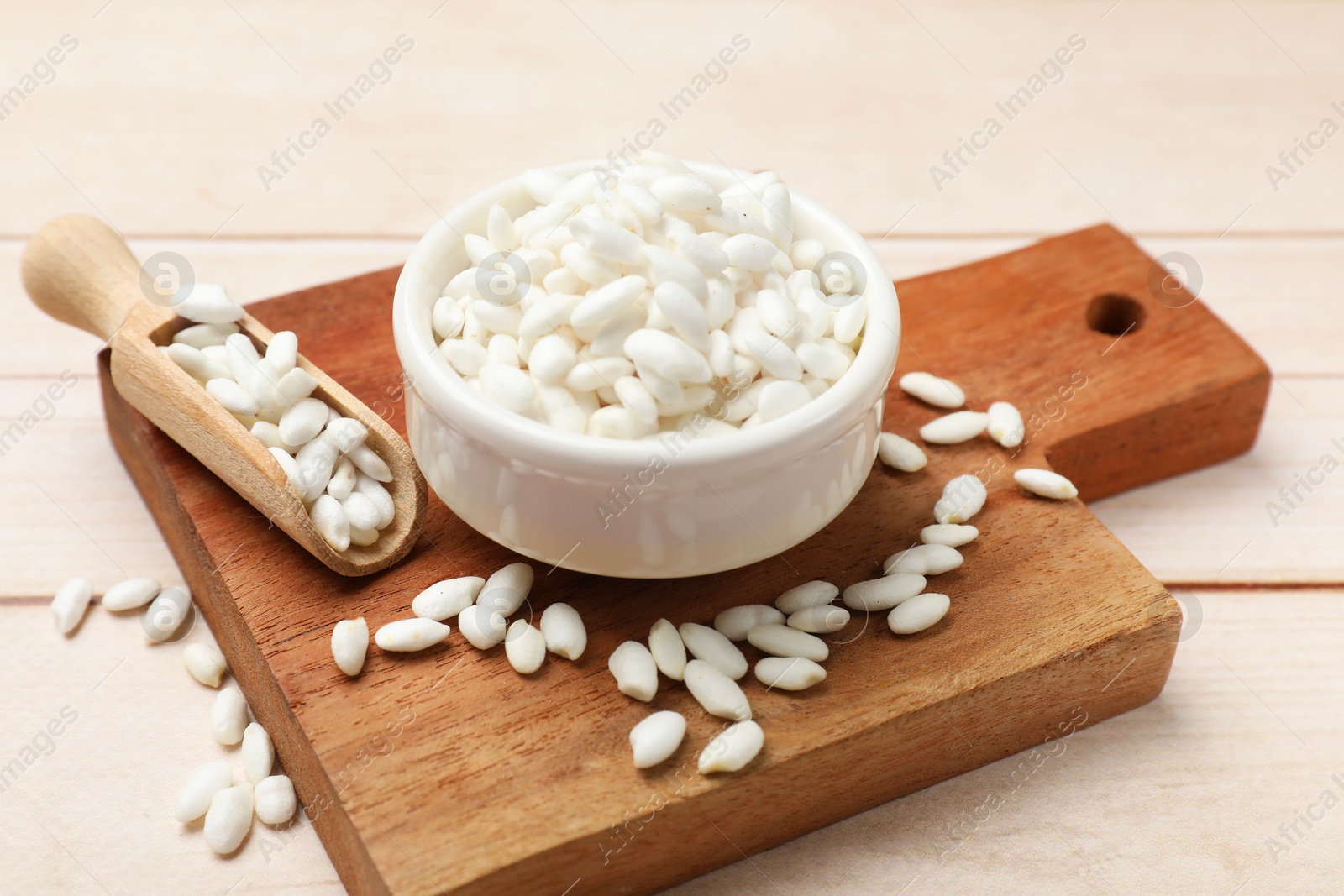 Photo of Bowl and scoop with puffed rice on white wooden table