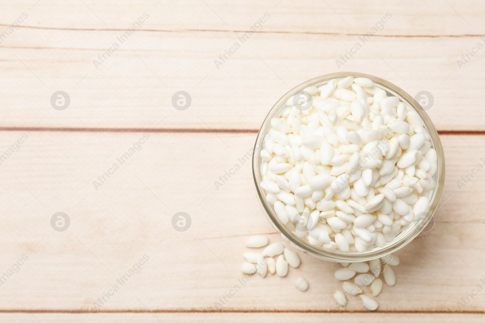 Photo of Puffed rice in bowl on white wooden table, top view. Space for text