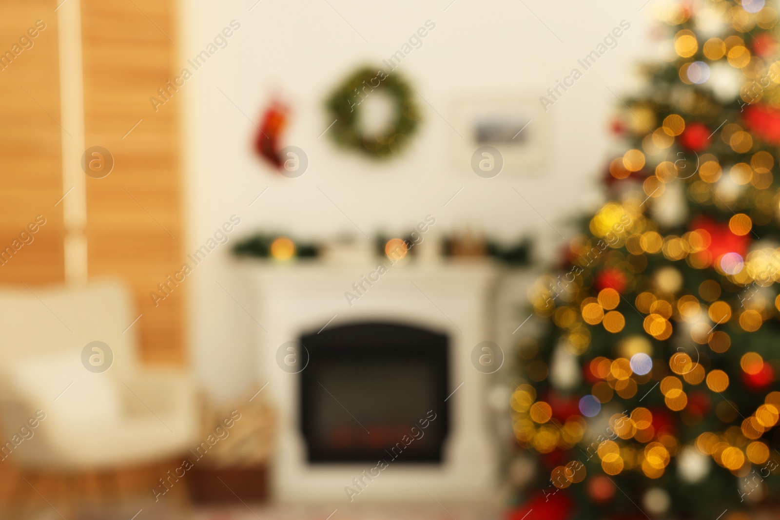 Photo of Blurred view of decorated Christmas tree near fireplace in room. Festive interior design