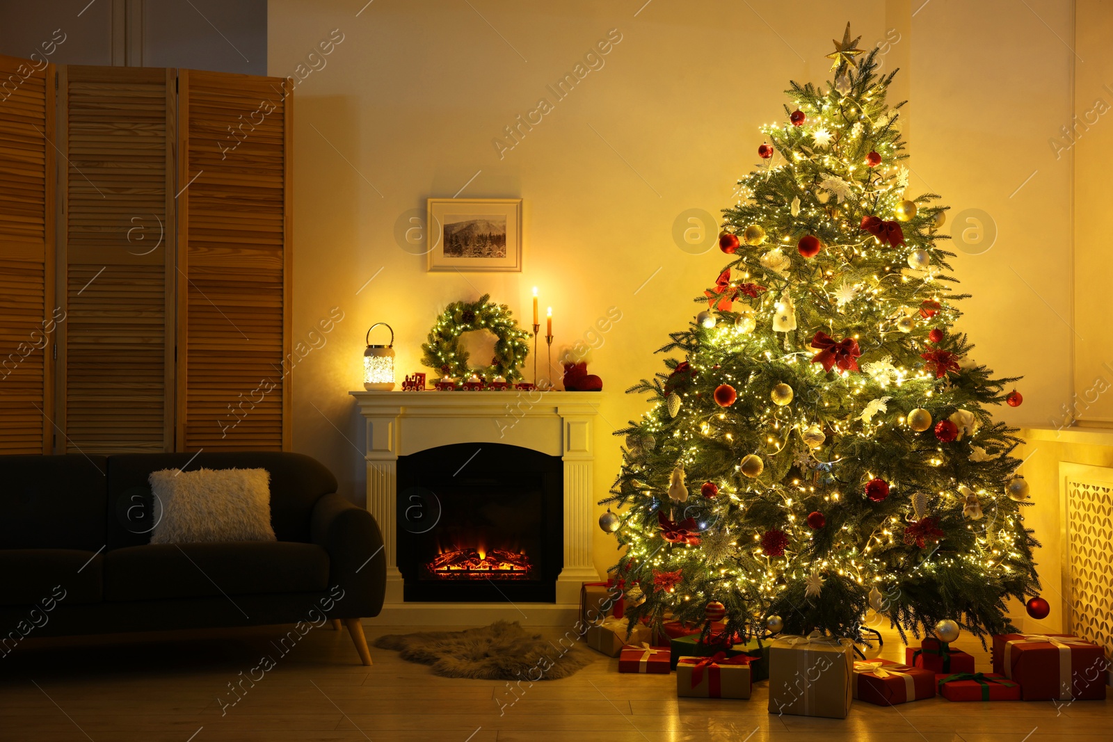 Photo of Decorated Christmas tree near fireplace in room. Festive interior design