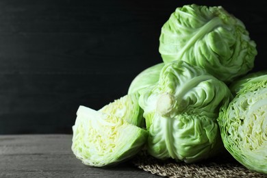 Photo of Whole and cut fresh cabbages on wooden table. Space for text