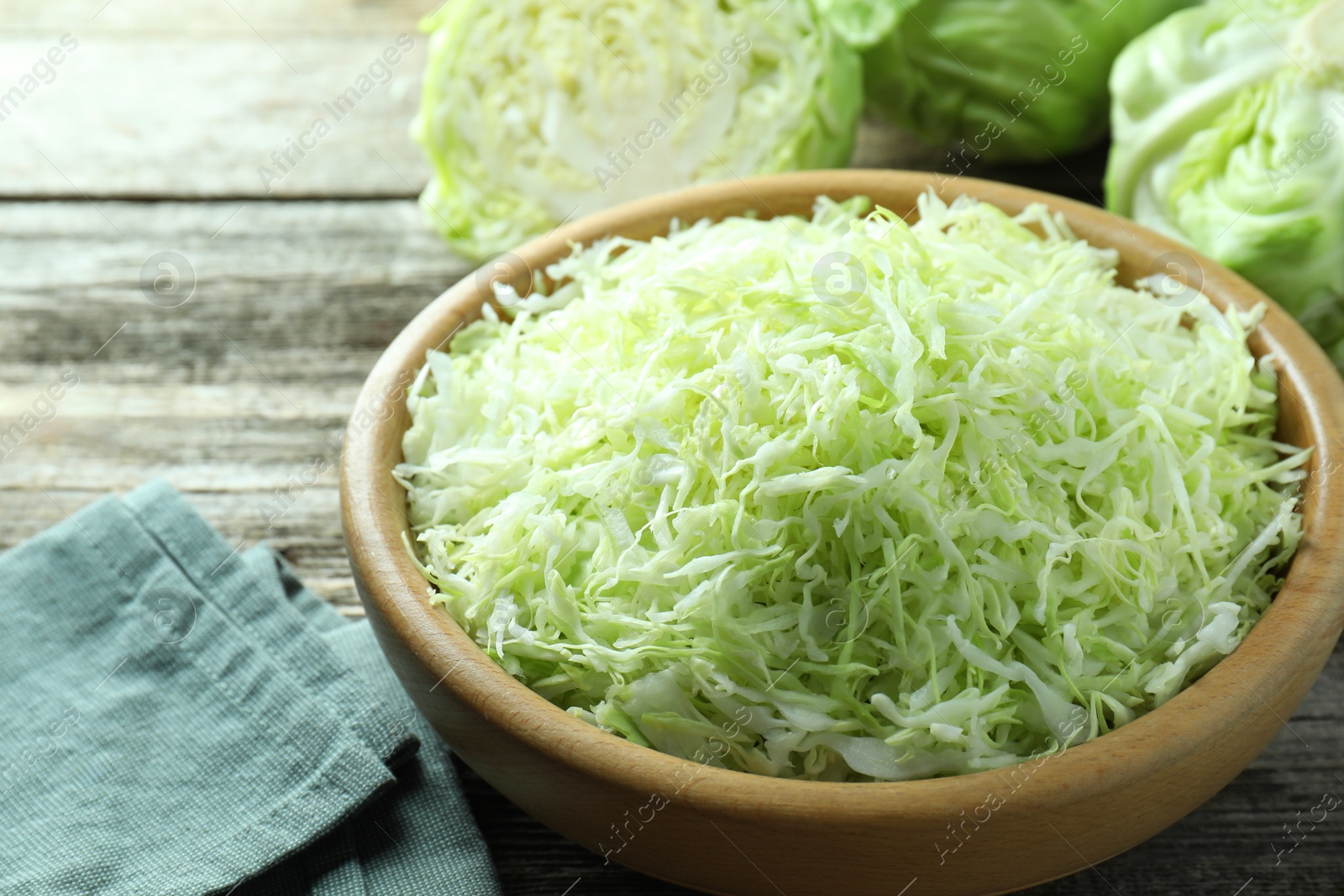 Photo of Fresh shredded cabbage on wooden table, closeup