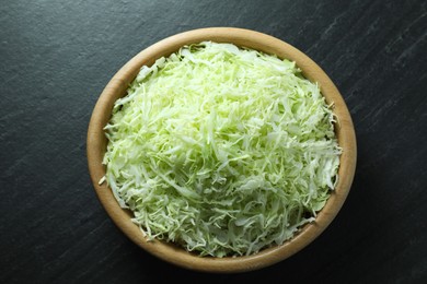 Photo of Fresh shredded cabbage on black table, top view