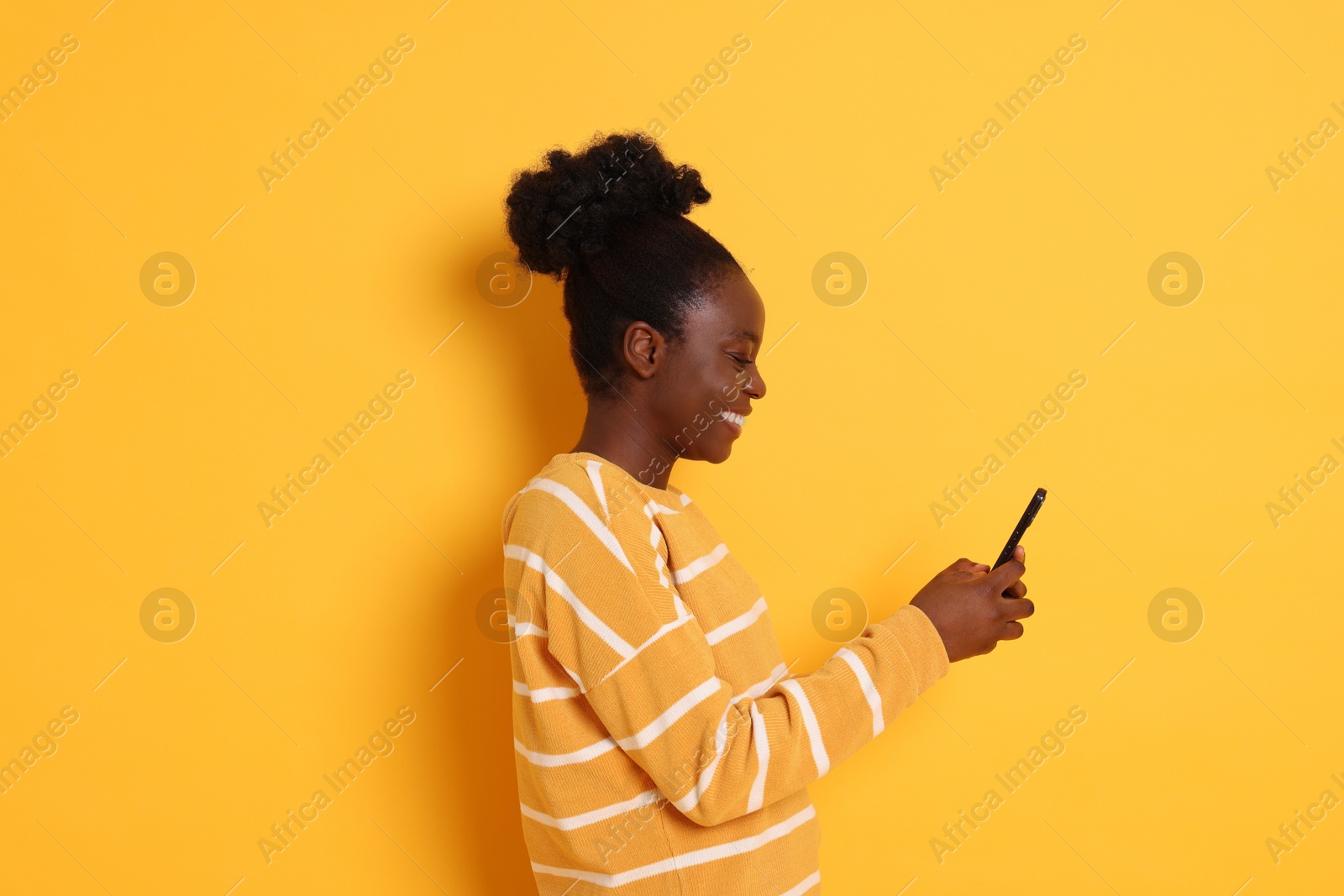 Photo of Happy woman with smartphone on yellow background