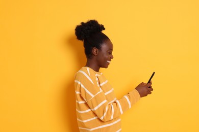 Photo of Happy woman with smartphone on yellow background