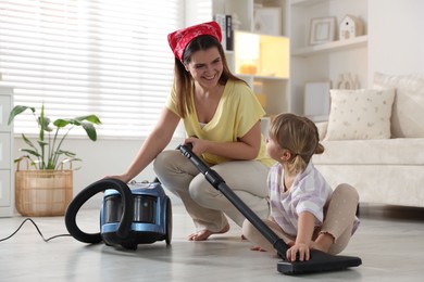 Photo of Little helper. Daughter and mother vacuuming together at home