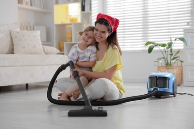 Photo of Little helper. Daughter and mother vacuuming together at home