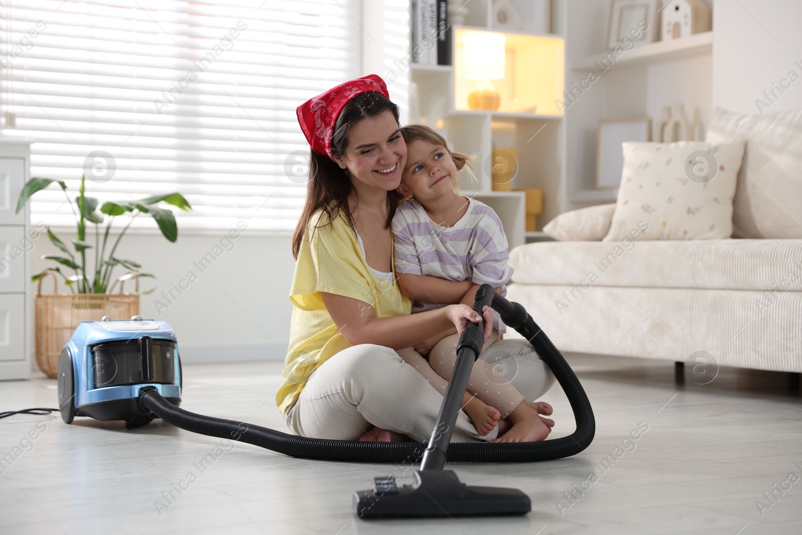 Photo of Little helper. Daughter and mother vacuuming together at home