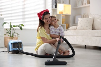 Little helper. Daughter and mother vacuuming together at home