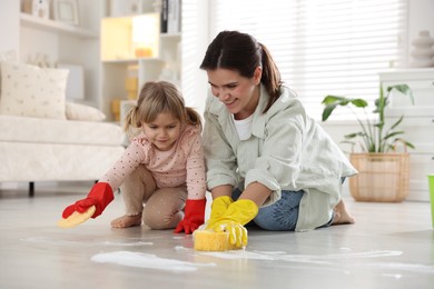 Photo of Little helper. Daughter and mother cleaning floor together at home