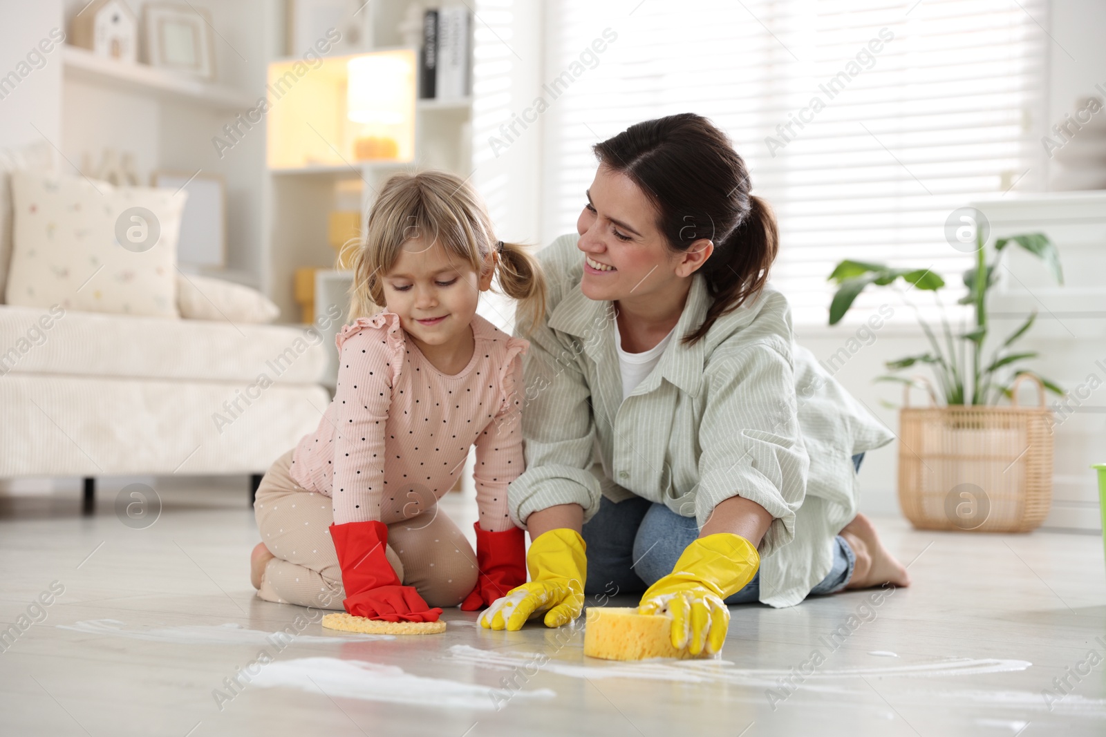 Photo of Little helper. Daughter and mother cleaning floor together at home