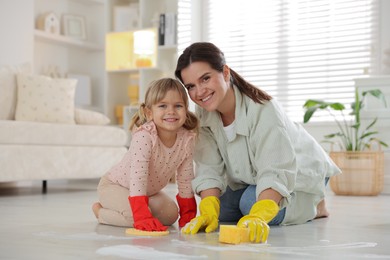 Little helper. Daughter and mother cleaning floor together at home