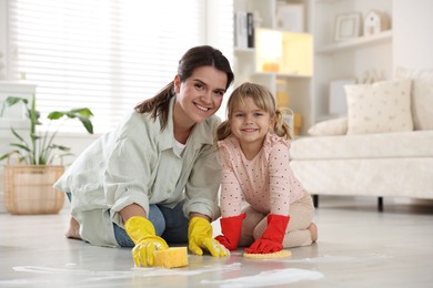 Little helper. Daughter and mother cleaning floor together at home