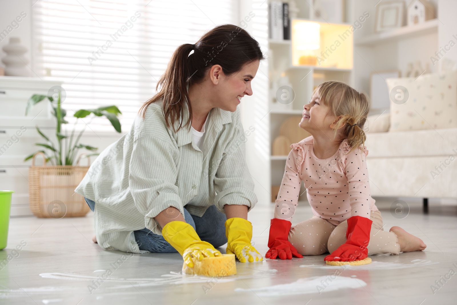 Photo of Little helper. Daughter and mother cleaning floor together at home