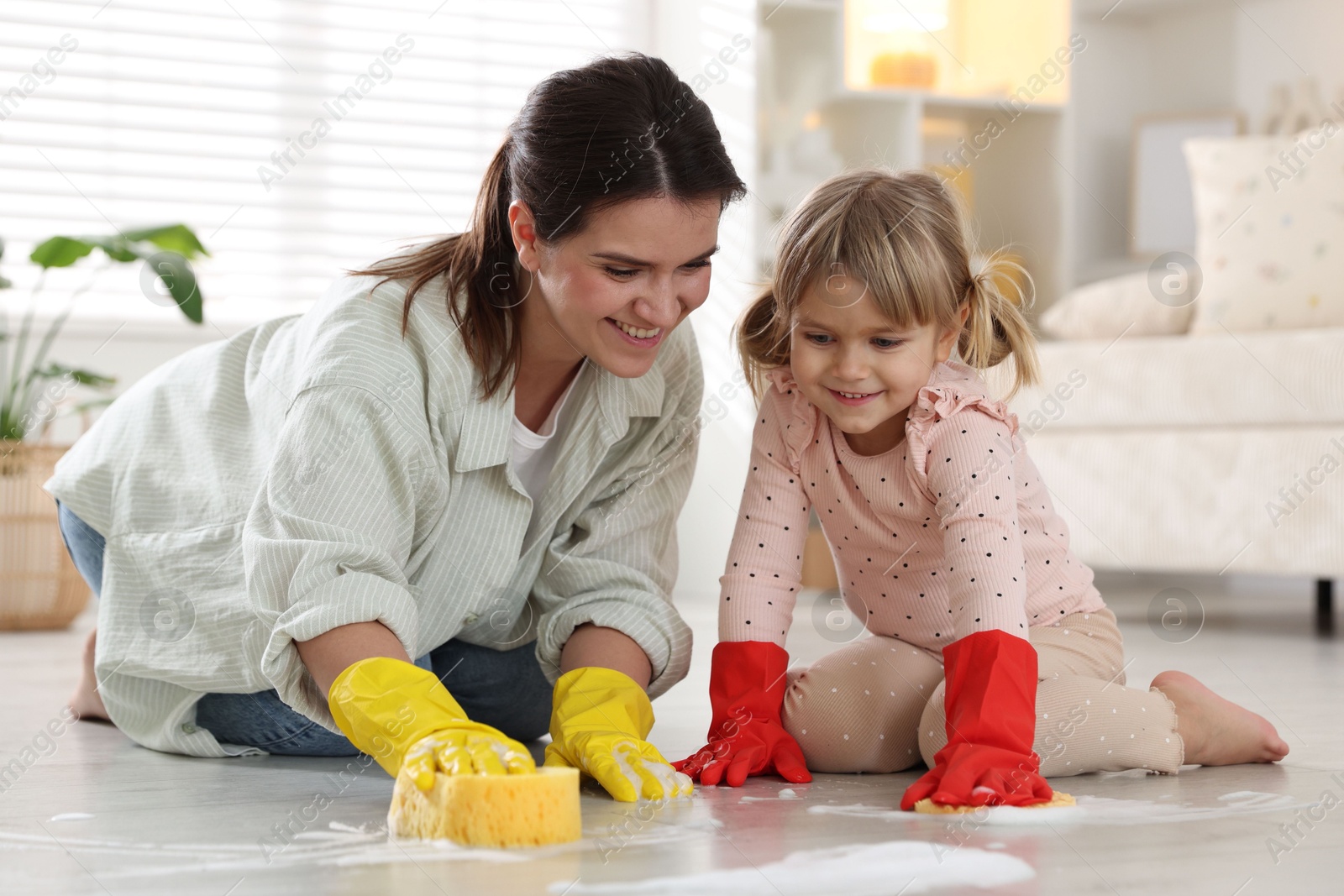 Photo of Little helper. Daughter and mother cleaning floor together at home