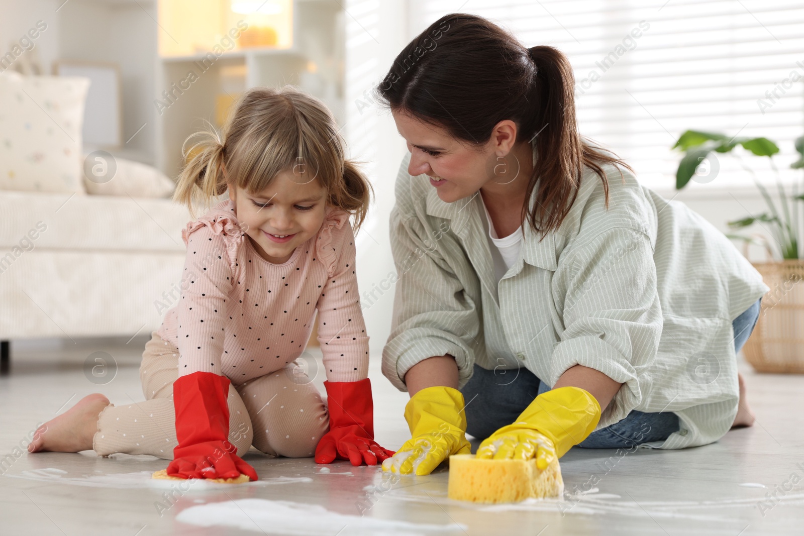 Photo of Little helper. Daughter and mother cleaning floor together at home