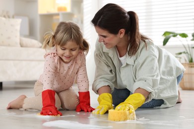 Photo of Little helper. Daughter and mother cleaning floor together at home