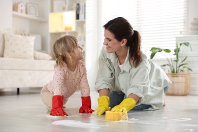 Photo of Little helper. Daughter and mother cleaning floor together at home