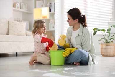 Photo of Cute little girl helping her mother cleaning floor at home