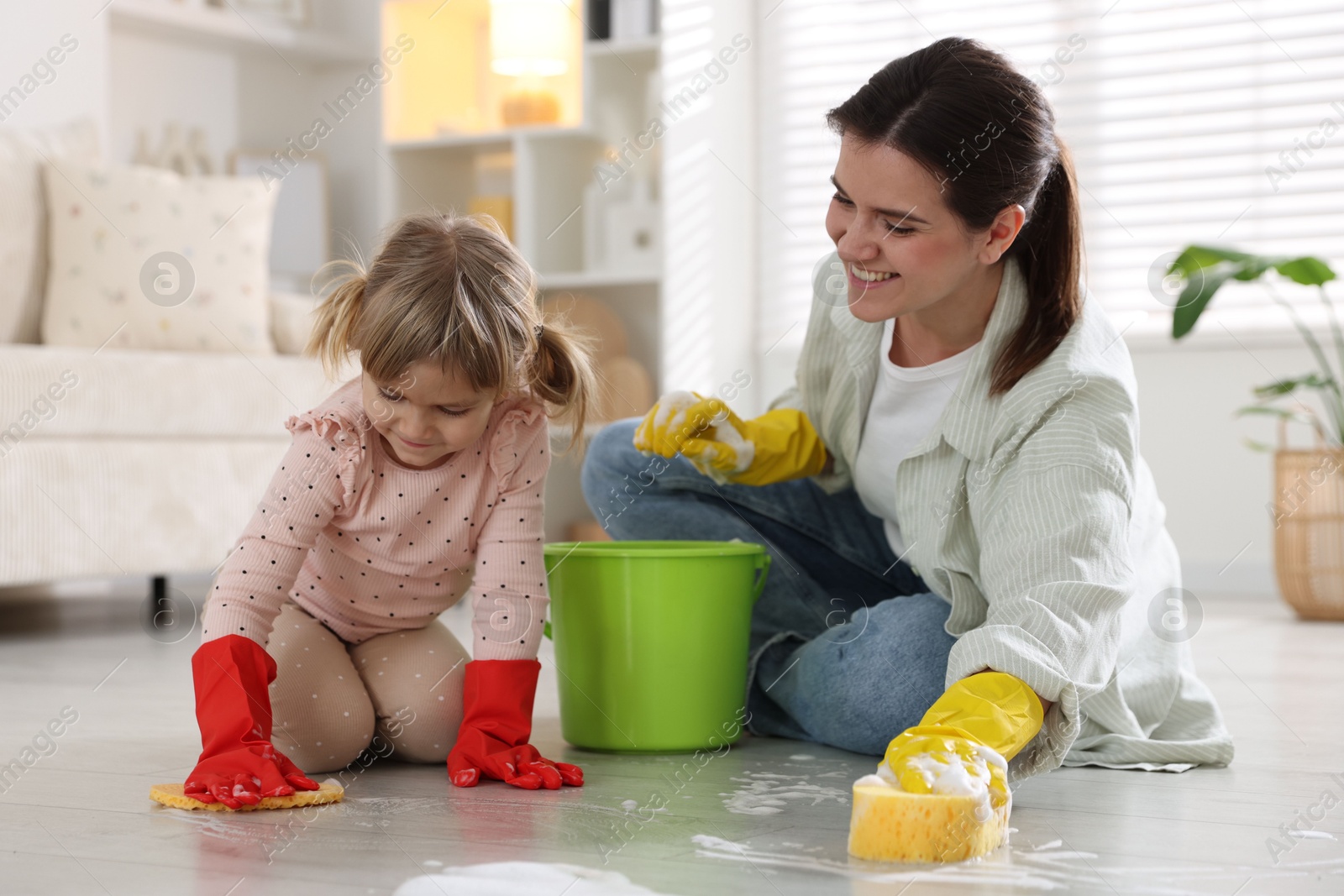 Photo of Little helper. Daughter and mother cleaning floor together at home