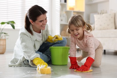 Photo of Little helper. Daughter and mother cleaning floor together at home