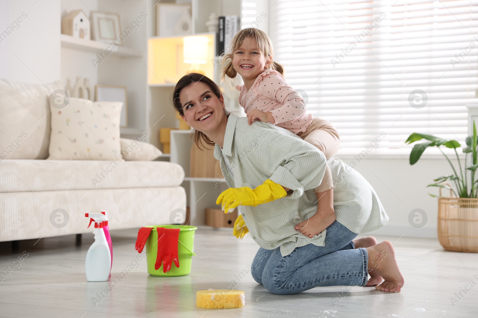 Photo of Little helper. Cute girl and her mother having fun while cleaning floor at home