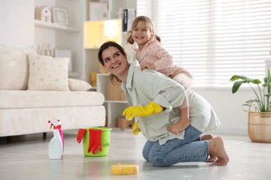 Little helper. Cute girl and her mother having fun while cleaning floor at home