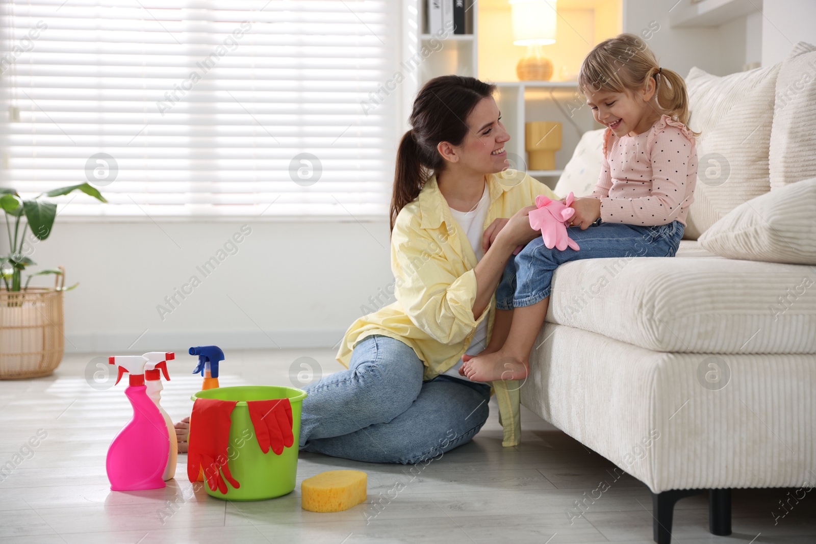 Photo of Little helper. Daughter and mother with rubber gloves at home