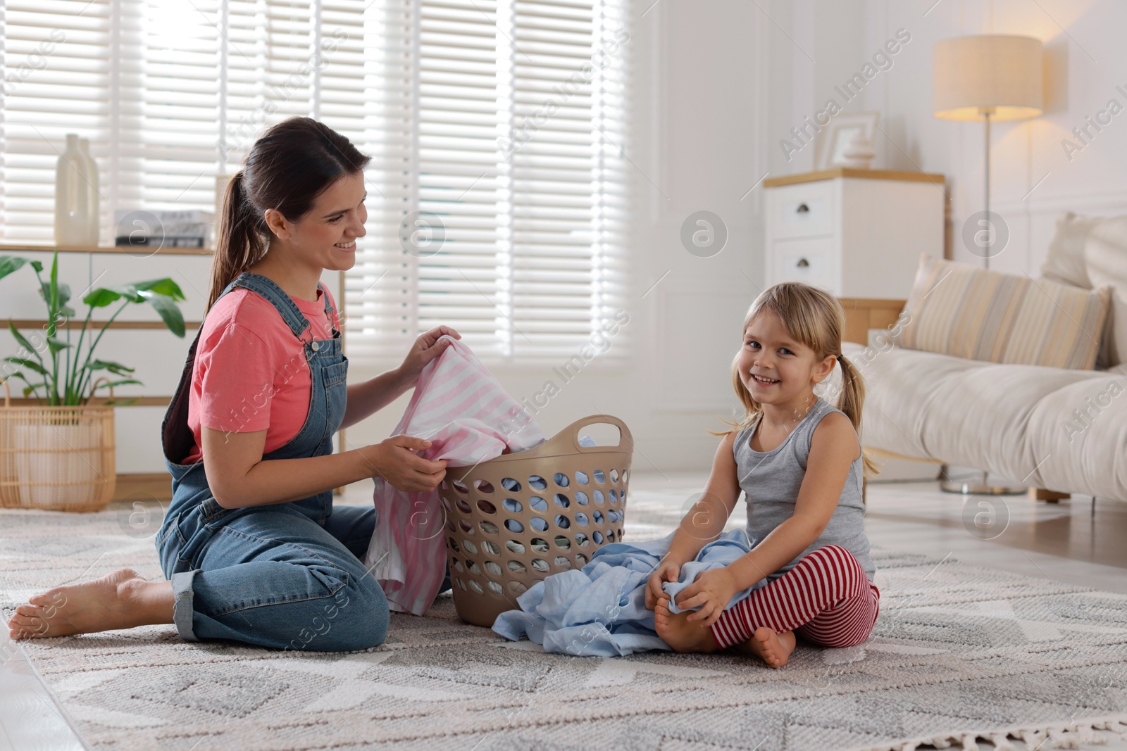 Photo of Little helper. Daughter and her mother with laundry at home