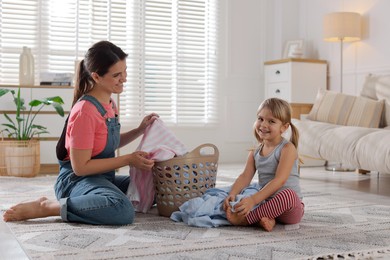 Photo of Little helper. Daughter and her mother with laundry at home