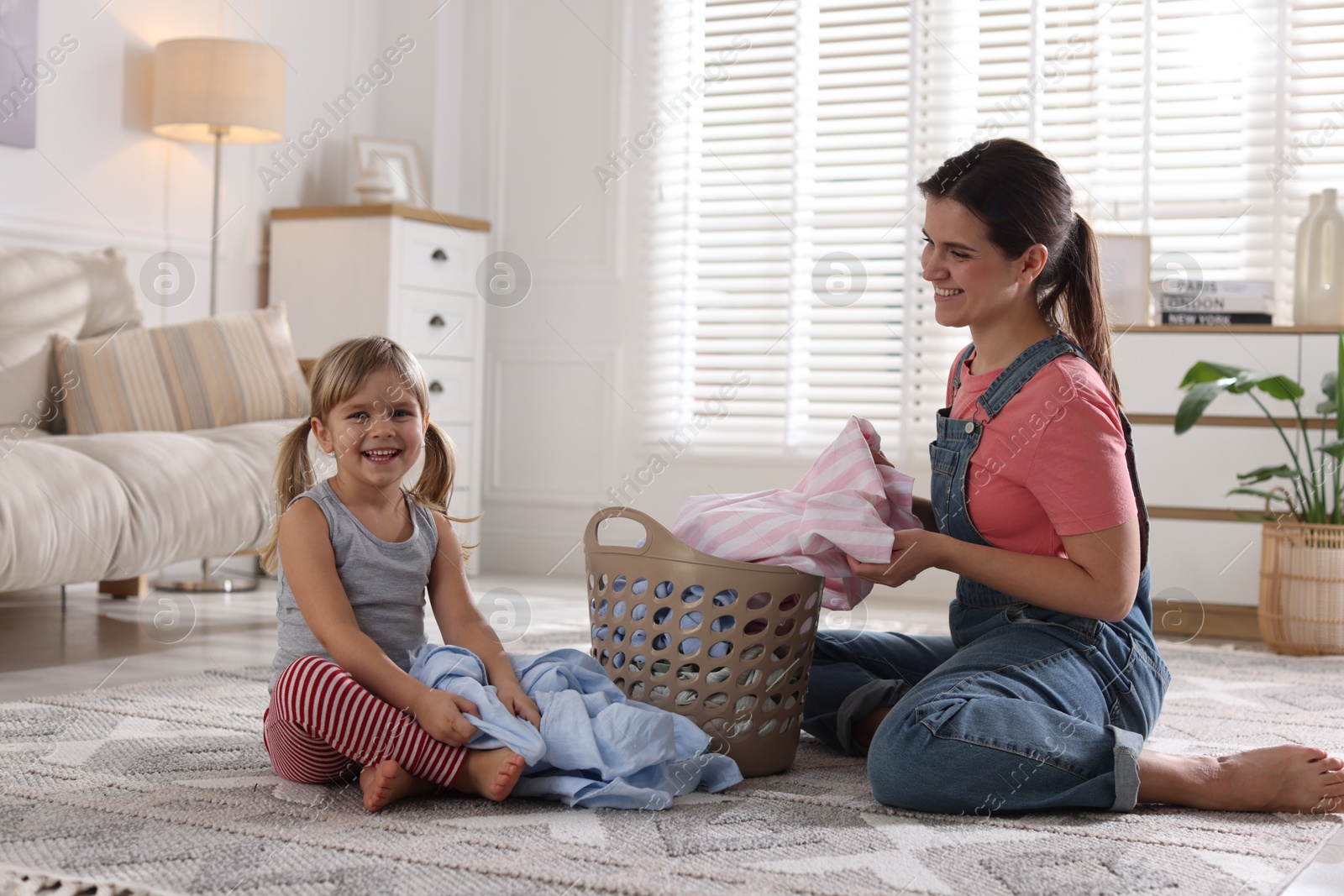 Photo of Little helper. Daughter and her mother with laundry at home