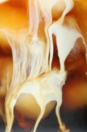 Photo of Refreshing coffee with ice and milk as background, closeup