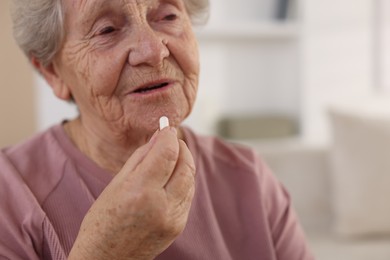 Photo of Senior woman taking medical pill at home, closeup. Space for text