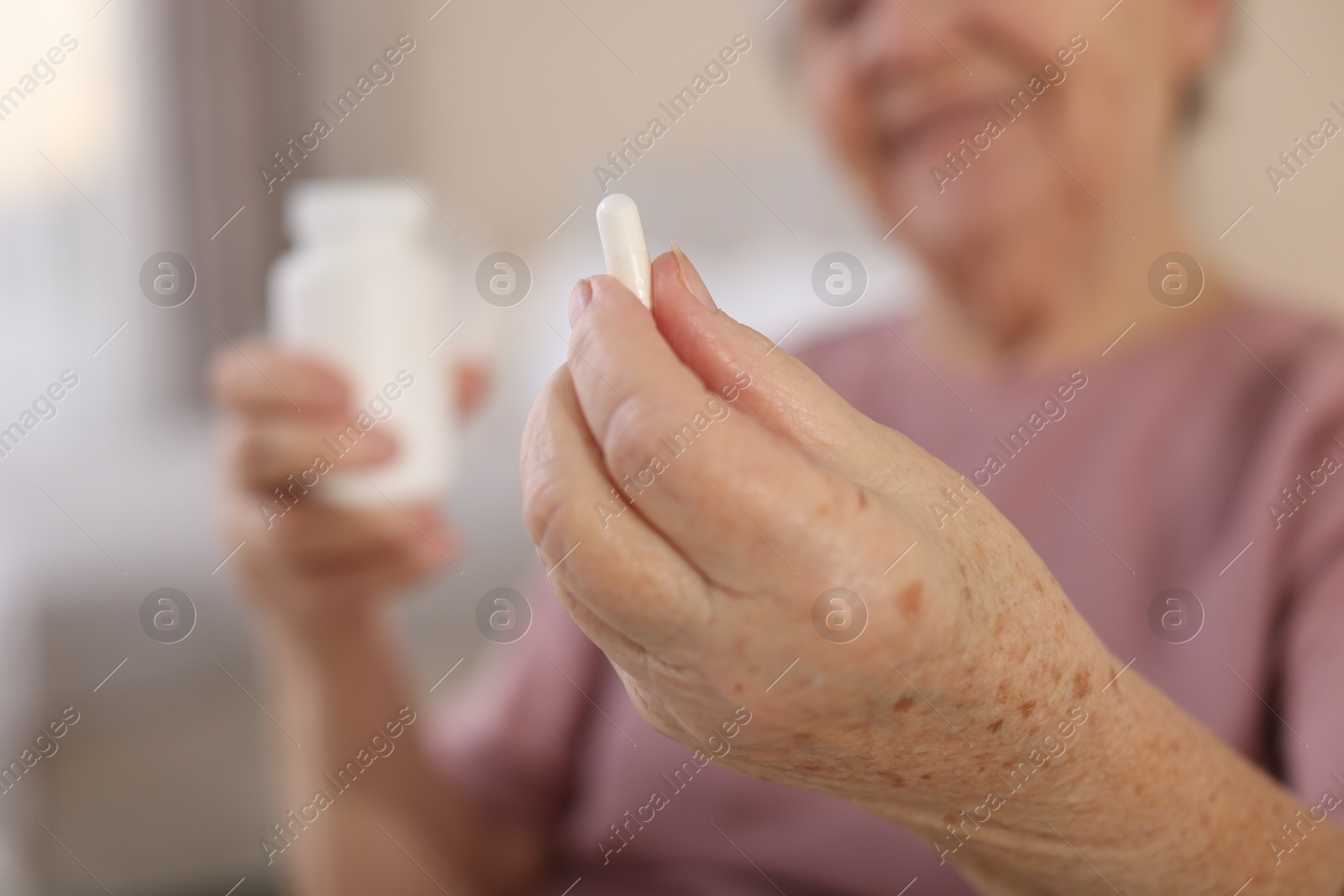 Photo of Senior woman with medical pill and bottle at home, selective focus