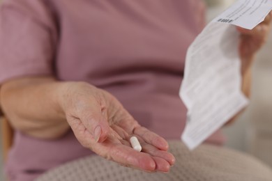 Photo of Senior woman with medical instruction and pill, closeup