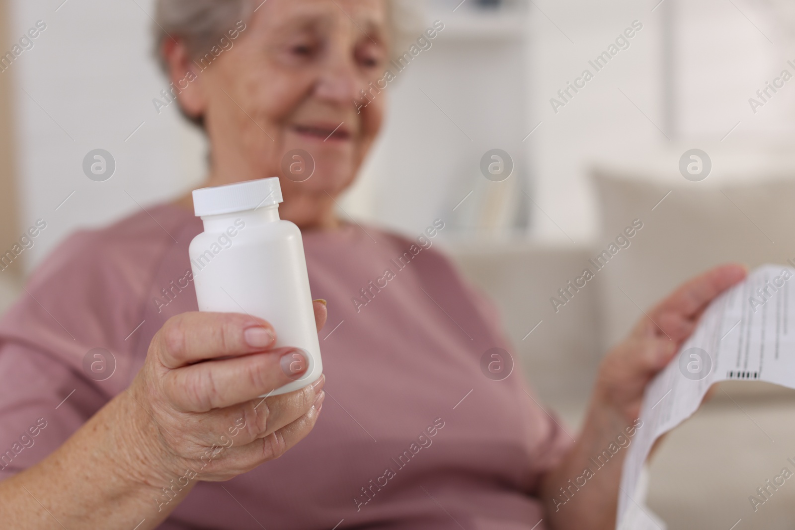 Photo of Senior woman with medical instruction and bottle of pills at home, selective focus