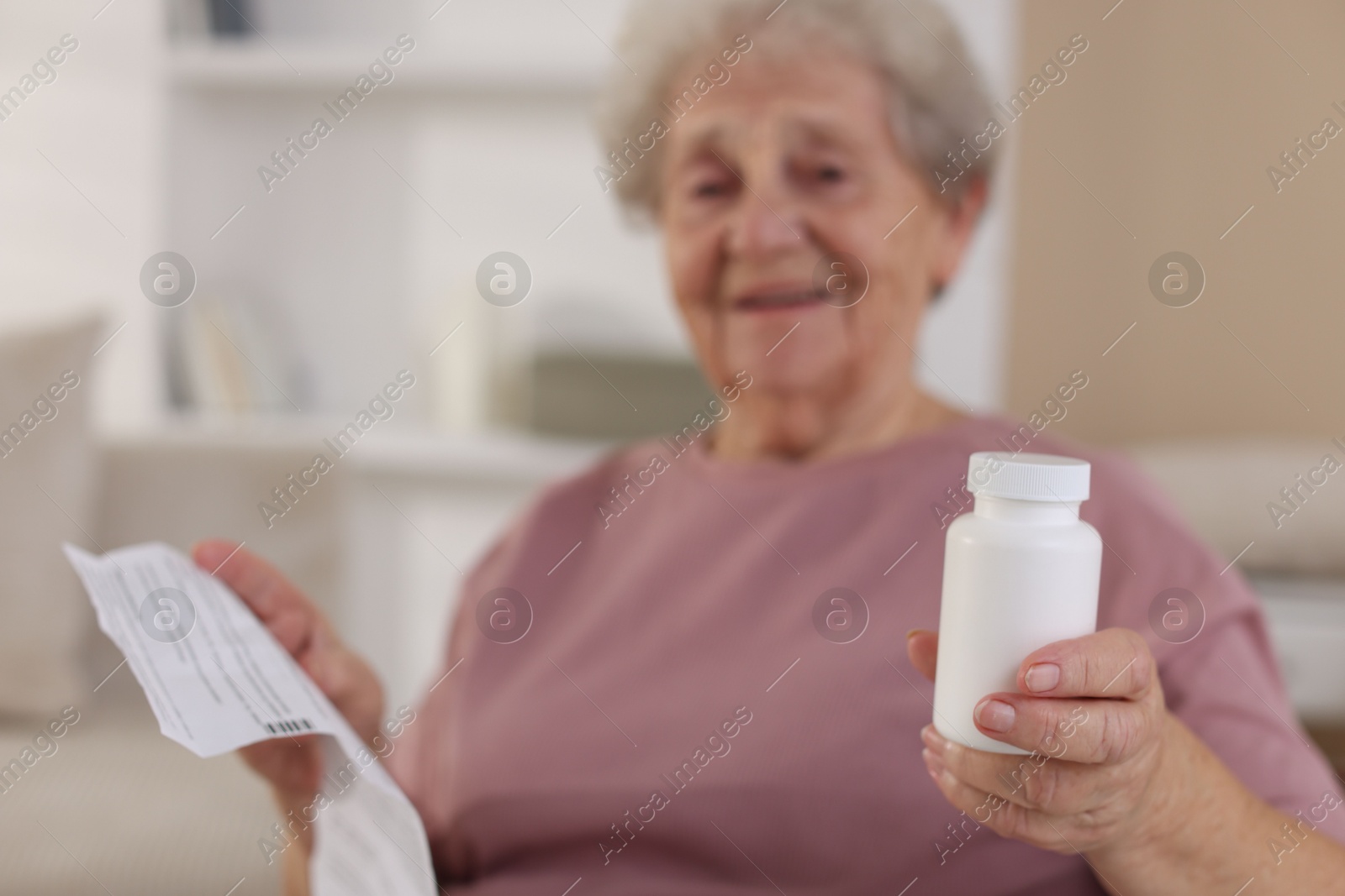 Photo of Senior woman with medical instruction and bottle of pills at home, selective focus