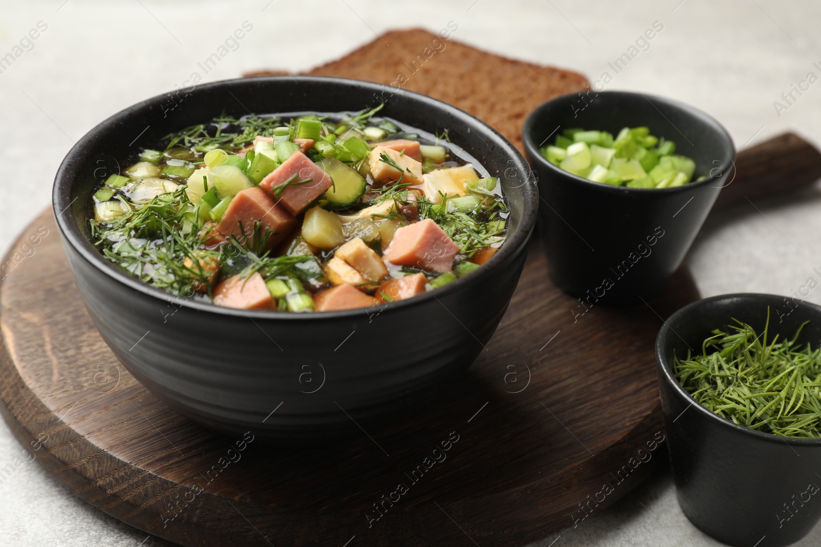 Photo of Delicious okroshka soup with kvass and ingredients on light table, closeup