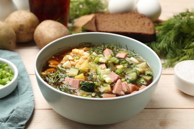 Photo of Delicious okroshka soup with kvass and ingredients on white wooden table, closeup