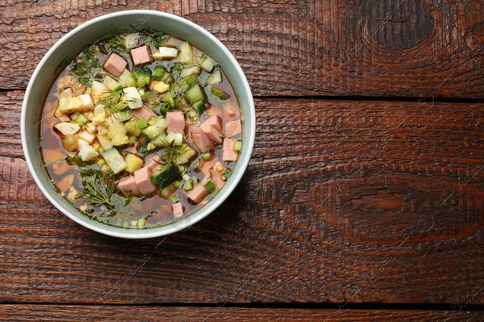 Photo of Delicious okroshka soup with kvass on wooden table, top view. Space for text