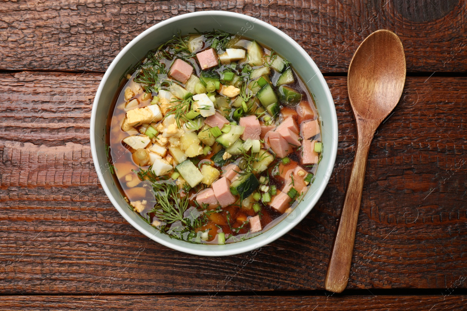 Photo of Delicious okroshka soup with kvass and spoon on wooden table, top view