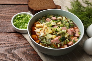 Photo of Delicious okroshka soup with kvass served on wooden table, closeup