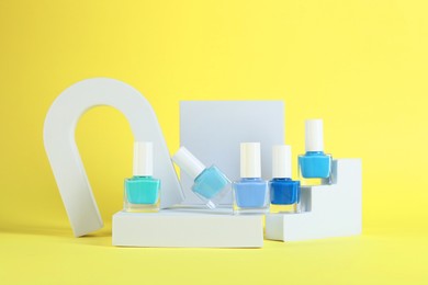 Photo of Stylish presentation of nail polishes in bottles on yellow background