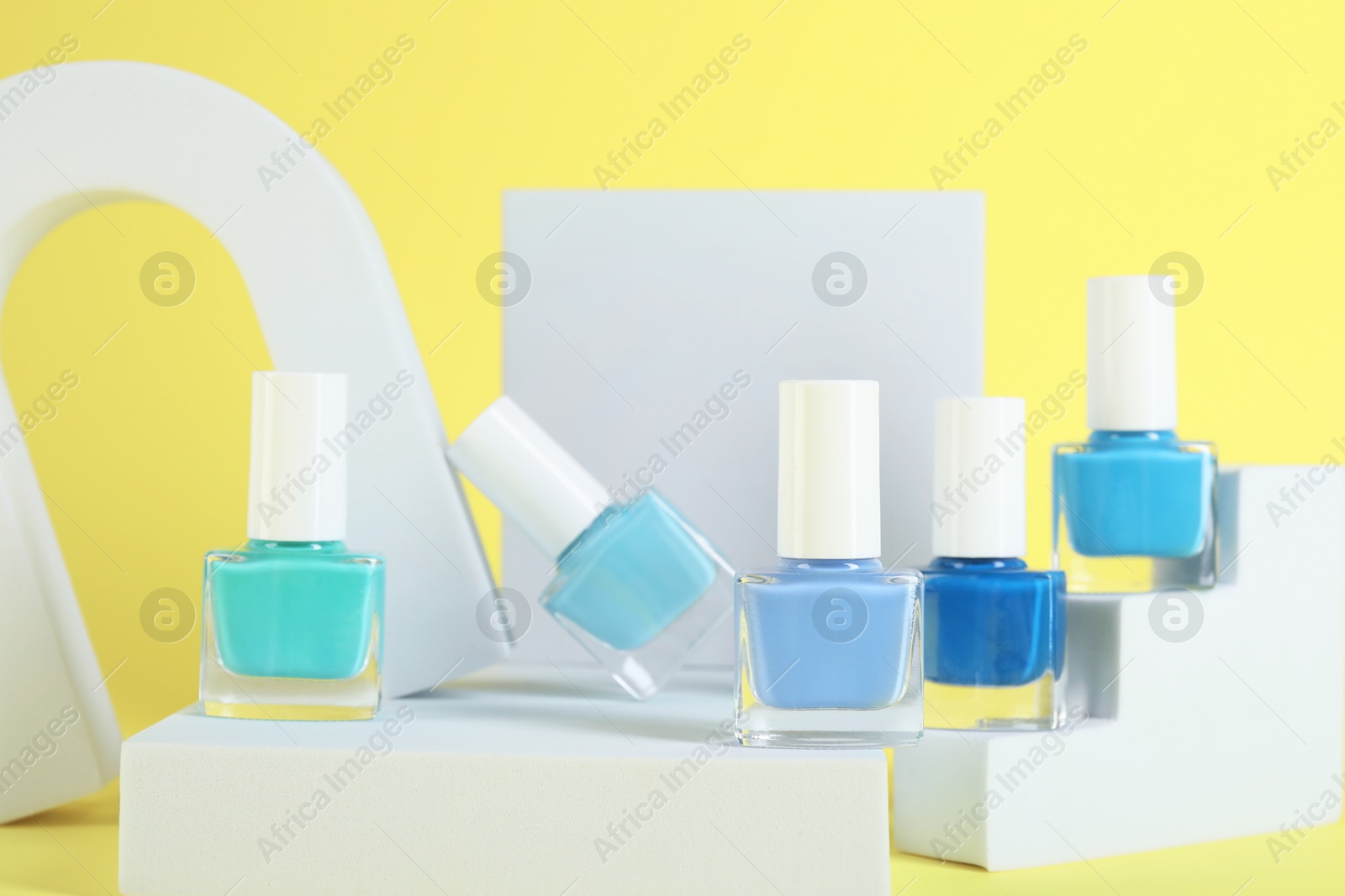 Photo of Stylish presentation of nail polishes in bottles on yellow background