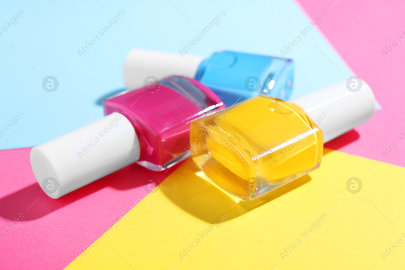 Photo of Bright nail polishes in bottles on color background, closeup