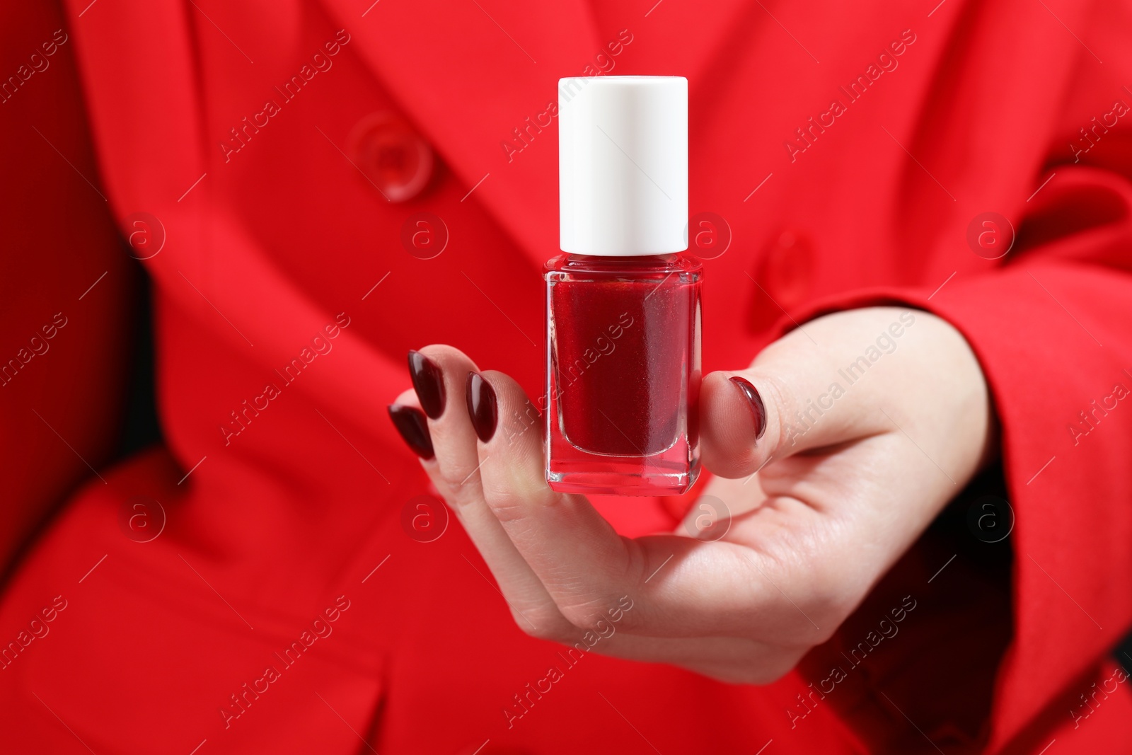 Photo of Woman holding bottle with red nail polish, closeup