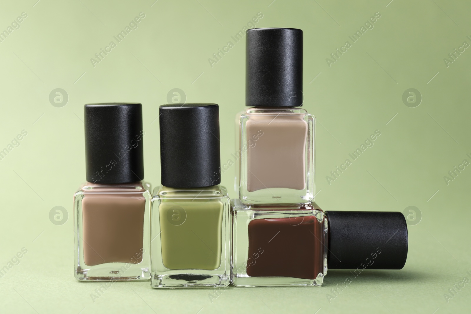 Photo of Nail polishes in bottles on olive background